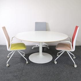 Möbelgrupp från Arper med ett vitt runt bord och tre färgglada stolar