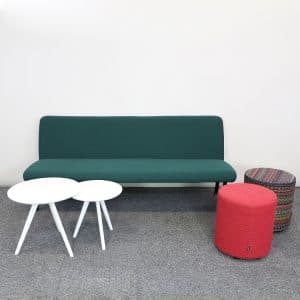 Loungegrupp med grön soffa, två sittpuffar och två vita små runda bord